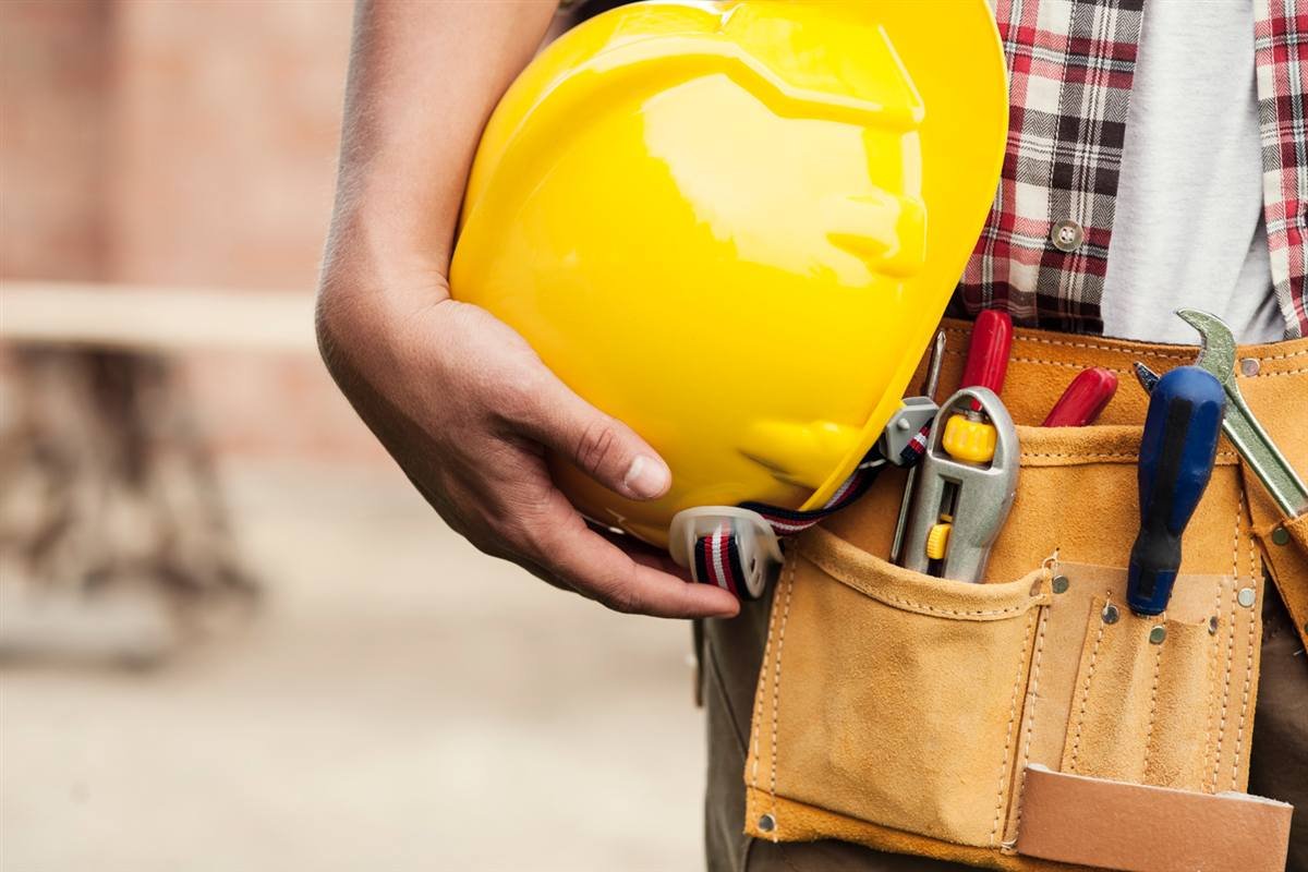 Engineer holding a safety helmet with tool belt